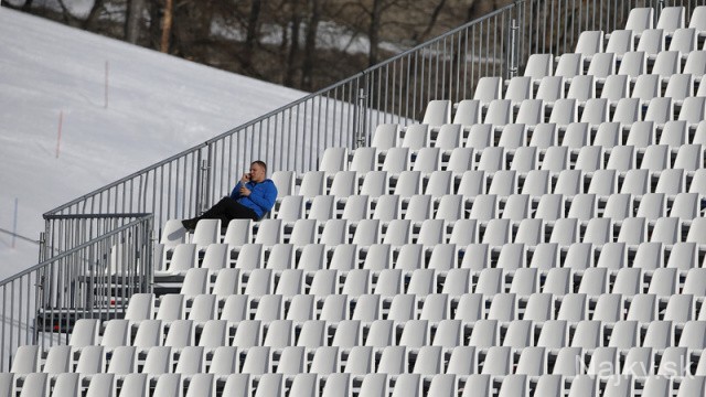 A spectator sits in an empty tribune at the downhill run of the women's alpine skiing super combined event during the 2014 Sochi Winter Olympics