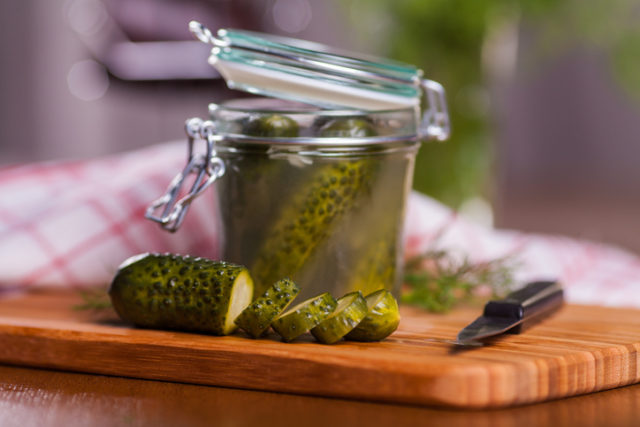 Pickled cucumbers in jar on cutting board