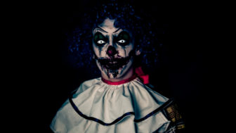 Crazy ugly grunge evil clown on Halloween making people scared