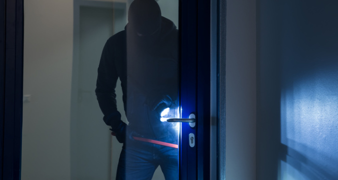 Burglar Using Crowbar To Open Glass Door