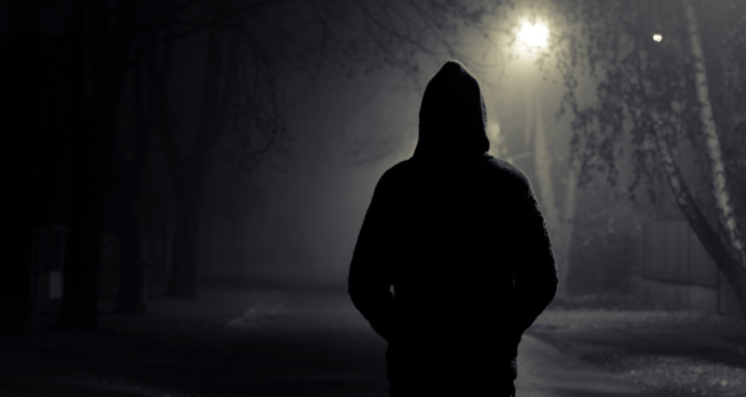 Silhouette of hooded person with spooky dark background