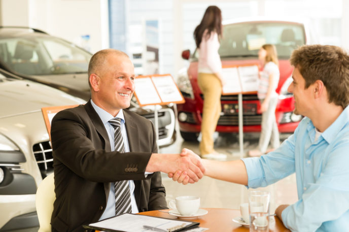 Customer and car salesman shaking hands
