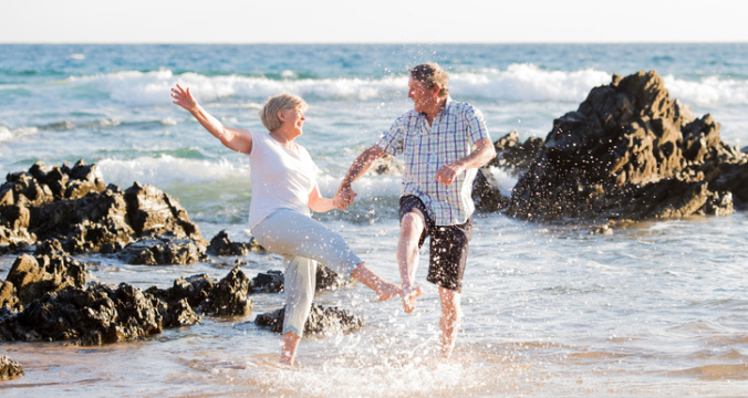 Lovely senior mature couple on their 60s or 70s retired walking happy and relaxed on beach sea shore in romantic aging together and retirement husband and wife lifestyle concept