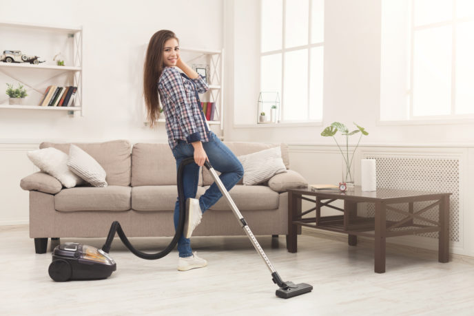 Happy woman cleaning home with vacuum cleaner