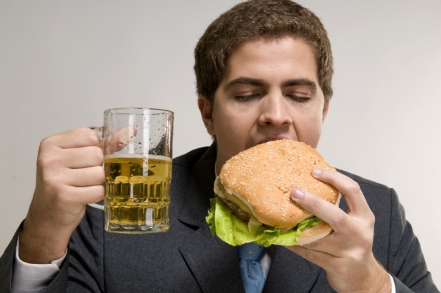 Muž v obleku drží pivo a je hamburger