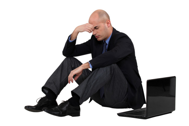 Muž v obleku sedí vedľa laptopu