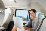 Žena sediaca na zadnom sedadle auta s laptopom na kolenách