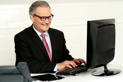 Usmievajúci sa muž pracuje na počítači