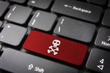 Internet business security concept: red key with skull icon on laptop keyboard. Included clipping path, so you can easily edit it.