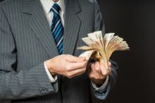 Businessman hand holding money, euro bills, stack of fifty euros