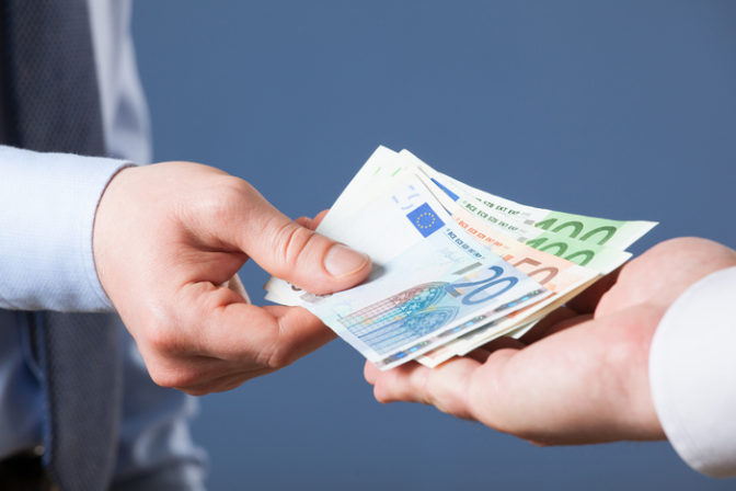 Businessman's hands exchanging euro on blue background