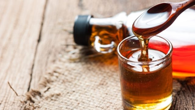 Maple syrup in glass bottle on wooden table
