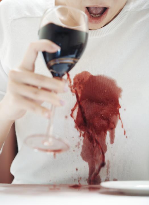 Shocked woman spilled red wine onto white shirt
