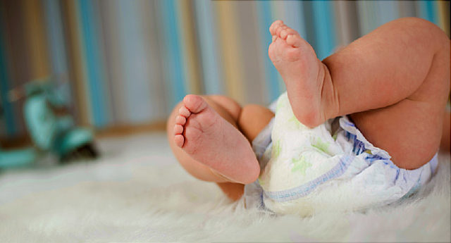 Newborn baby in diaper lying on plush blanket