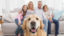 Family sitting on the couch with golden retriever in foreground
