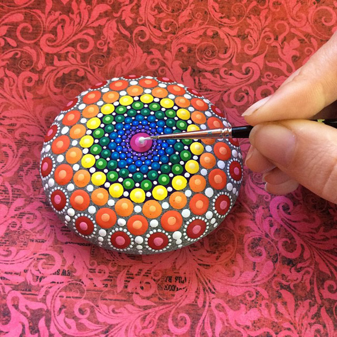 Artist finishes one of her rainbow colored mandala stones.jpeg