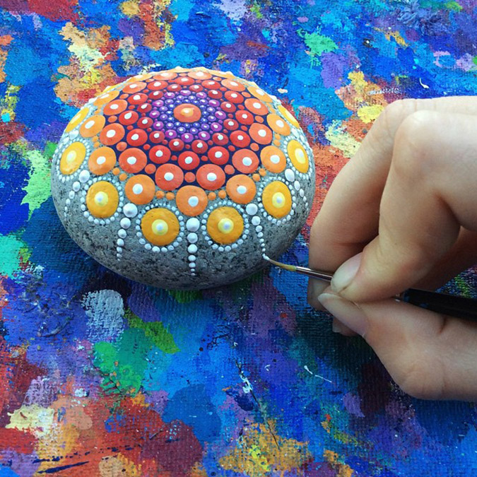 Artist paints one of her mandala stones.jpeg