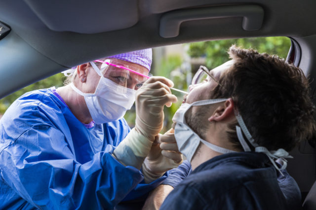 A doctor taking a nasal swab from a driver