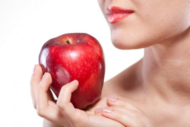 Žena držiaca červené jablko