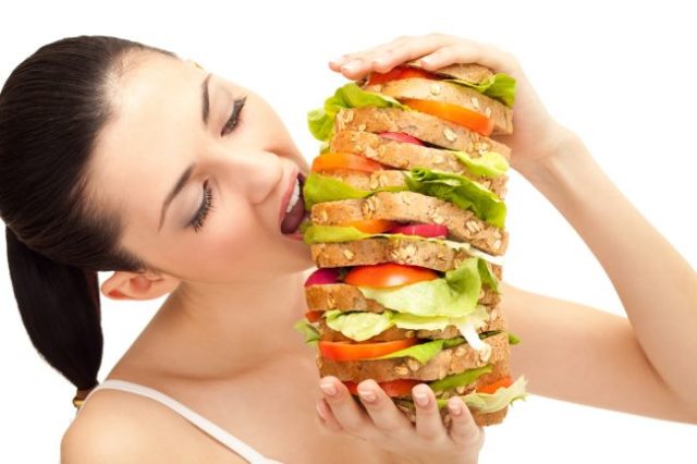 Žena jediaca veľký zeleninový sendvič