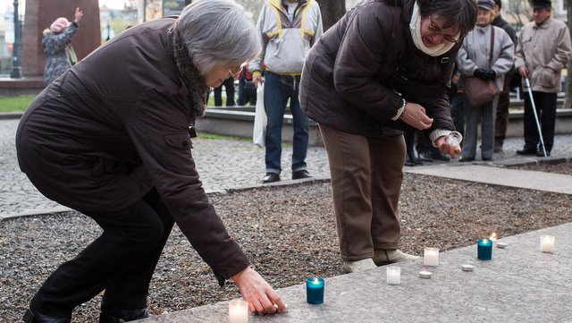 Ľudia zapaľujú sviečky počas verejného zhromaždenia pri príležitosti výročia sviečkovej manifestácie.