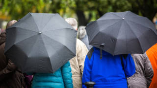 Návštevníci mesta s dáždnikmi v upršanom jesennom počasí na Námestí slobody.