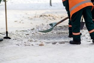 Workers sweep snow from road in winter. Cleaning road from snow storm