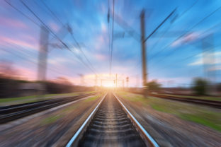 Railway station with motion blur effect at sunset. Blurred railroad. Industrial conceptual landscape with blurred railway station,  blue sky with colorful clouds and sunlight. Railway track.Background