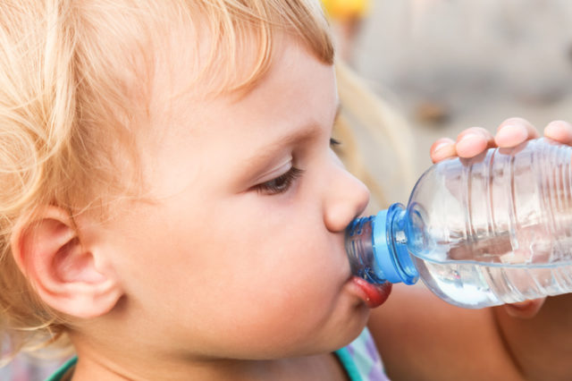 Caucasian child drink water from plastic bottle