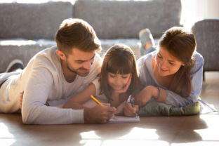 Couple and daughter lying on warm floor and drawing