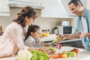 Happy smiling family making salad together at kitchen