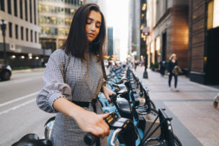 Girl renting a city bike from a bike stand