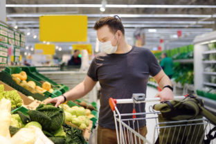 Man wearing disposable medical mask shopping in supermarket during coronavirus pneumonia outbreak