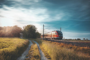 Red German train traveling on railway tracks through nature