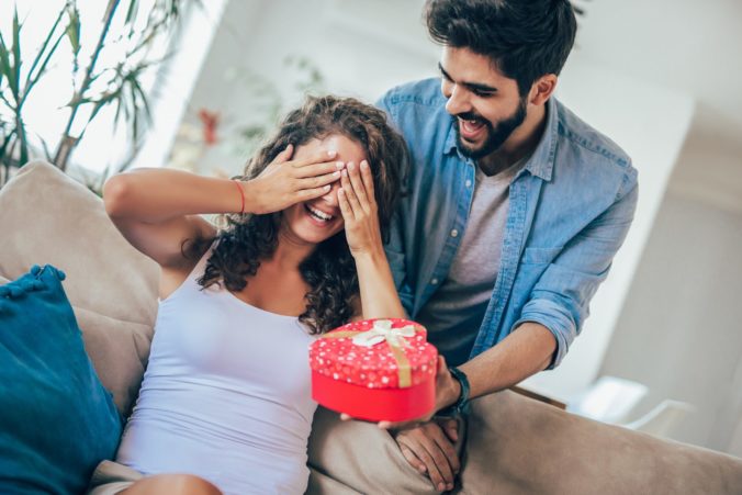 Man giving a surprise gift to woman at home