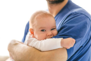 Satisfied kid in the arms of dad. Divide the responsibilities of caring for a child between spouses
