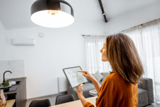 Woman controlling light with a digital tablet at home