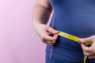 Overweight woman with measuring tape on waistline, closeup