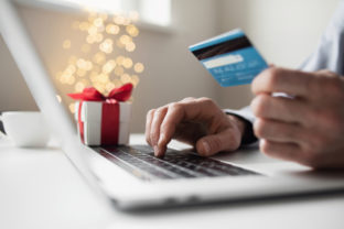 Online shopping during holidays. Man ordering Christmas gift using laptop and credit card