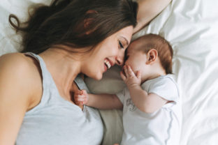 Young mother having fun with cute baby girl on the bed, natural tones, love emotion