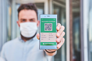 Hand man holds smartphone displaying on app mobile valid digital green vaccination certificate for Covid 19