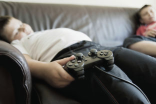 Boys Sleeping On Sofa While Holding Games Consoles