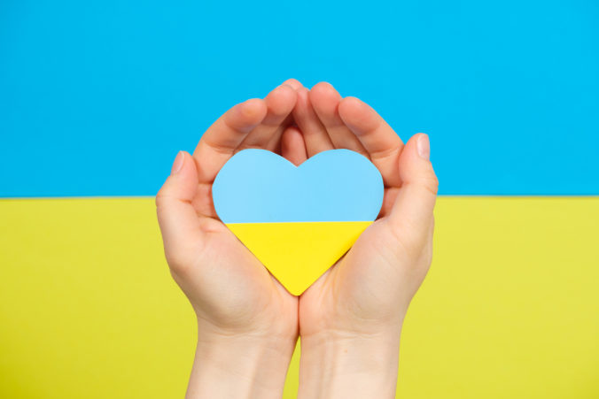 Yellow blue heart in the color of the flag of Ukraine in the hands of a person, a place for text. Love for one's country, Constitution Day and Independence Day