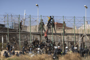 Migrants climb the fences separating the Spanish enclave of Melilla from Morocco in Melilla, Spain, Friday, June 24, 2022. Dozens of migrants stormed the border crossing between Morocco and the Spanish enclave city of Melilla on Friday in what is the first such incursion since Spain and Morocco mended diplomatic relations last month