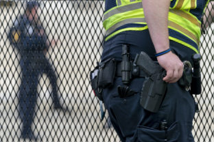 A Capitol Police Officer rests his hand near his gun as he works by the anti-scaling fencing outside the Supreme Court