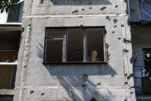 An elderly woman looks out of her apartment window in a damaged building from a May rocket attack in Sloviansk, Donetsk region, eastern Ukraine, Saturday, Aug. 6, 2022. ()