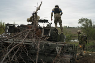 Ukrainian servicemen stand atop a destroyed Russian tank in a retaken area near the border with Russia in Kharkiv region, Ukraine