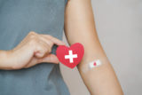 Senior human hand holding red paper heart shape and red blood drop symbol on bandage for world blood donation and donor day and save life concept
