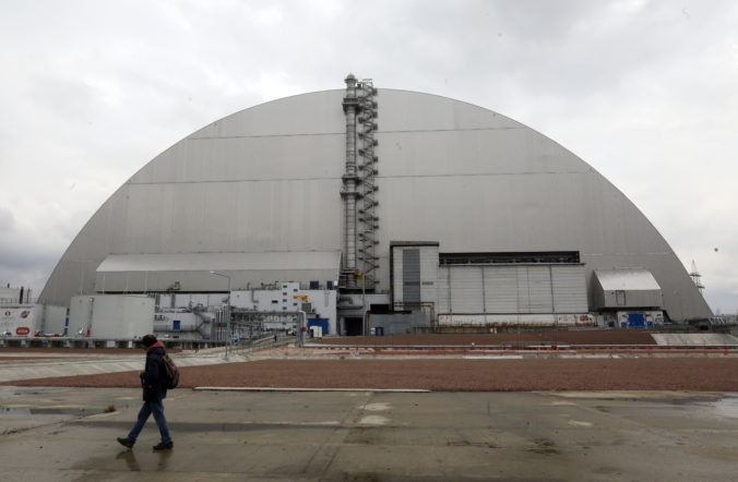 FILE - A man walks past a shelter covering the exploded reactor at the Chernobyl nuclear plant, in Chernobyl, Ukraine, Thursday, April 15, 2021. When fighting from Russia’s invasion of Ukraine resulted in power cuts to the critical cooling system at the closed Chernobyl nuclear power plant, some feared that spent nuclear fuel would overheat. But nuclear experts say there’s no imminent danger because time and physics are on safety's side