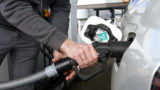 Close up of a man refueling a white hydrogen fuel cell car. At a hydrogen refueling station.
